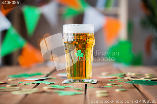 Image of glass of beer, shamrock and coins on wooden table