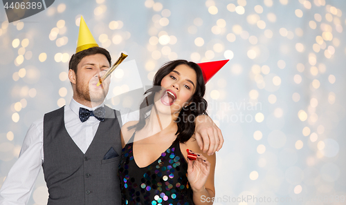 Image of happy couple with party blowers having fun