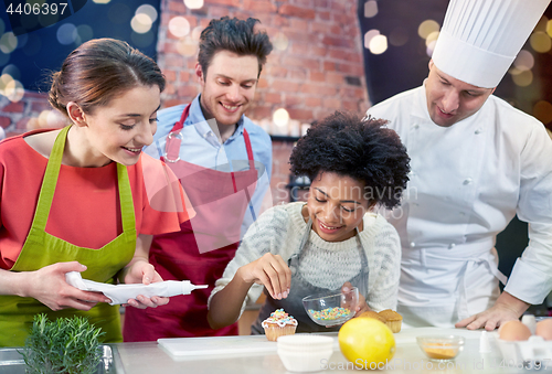 Image of happy friends and chef cook baking in kitchen