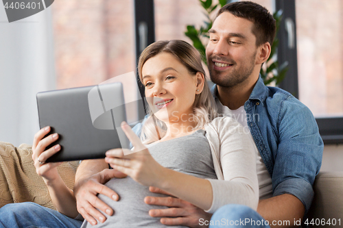 Image of man and pregnant woman with tablet pc at home