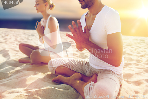 Image of close up of couple meditating on beach