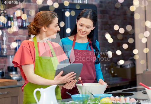 Image of happy women with tablet pc cooking in kitchen