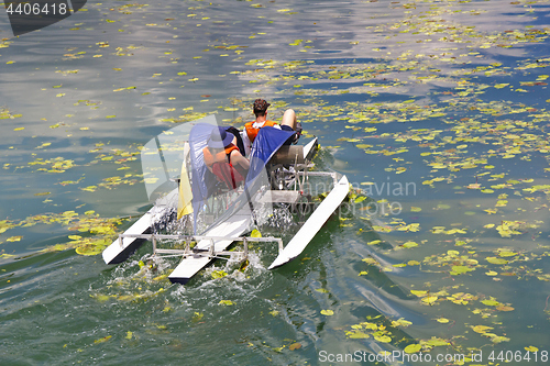 Image of Man and woman ride with floating pedal bicycle boats across the 