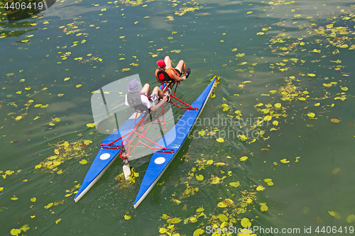 Image of Man and woman ride with floating pedal bicycle boats across the 