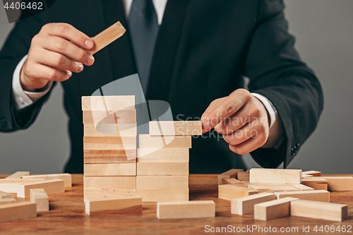 Image of Man and wooden cubes on table. Management concept