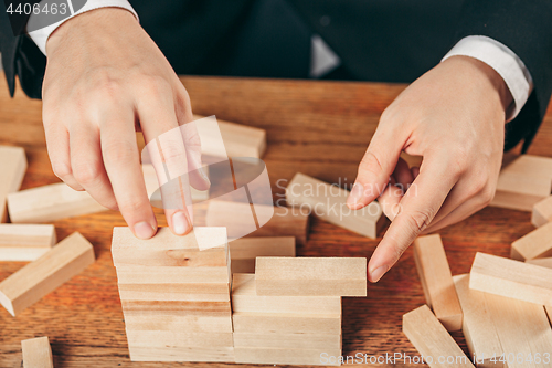 Image of Man and wooden cubes on table. Management concept