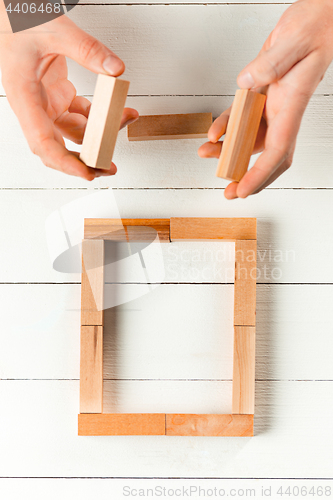 Image of Man and wooden cubes on table. Management concept