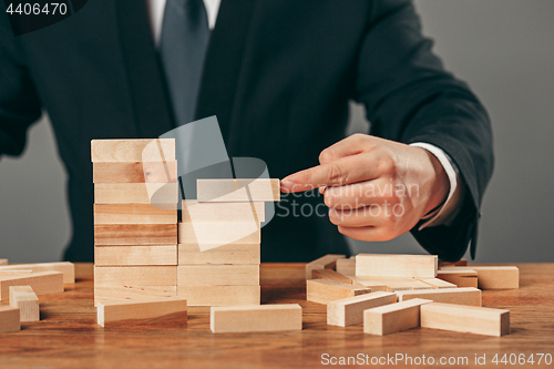 Image of Man and wooden cubes on table. Management concept