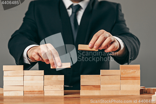 Image of Man and wooden cubes on table. Management concept