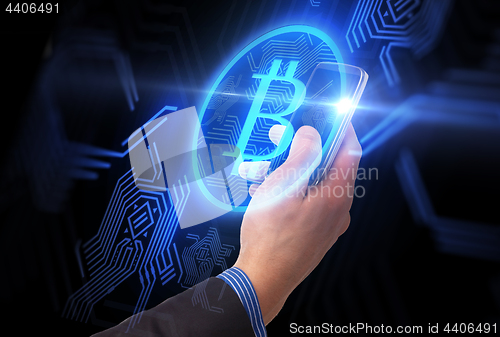 Image of close up of hand with smartphone and bitcoin