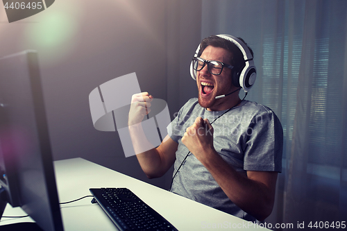 Image of man in headset playing computer video game at home