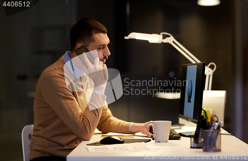 Image of man with smartphone working late at night office