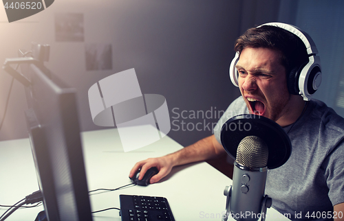 Image of man in headset playing computer video game at home