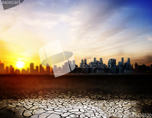 Image of cracked desert surface over sunset in city