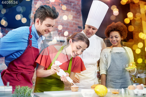 Image of happy friends and chef cook baking in kitchen