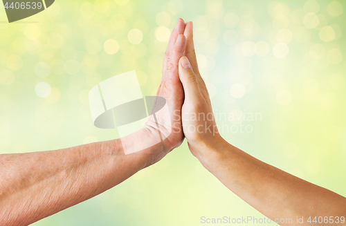 Image of close up of senior and young woman hands touch