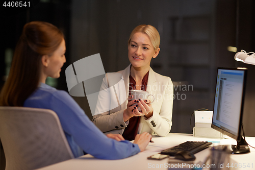 Image of businesswomen drinking coffee at night office