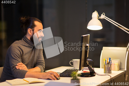 Image of creative man with computer working at night office