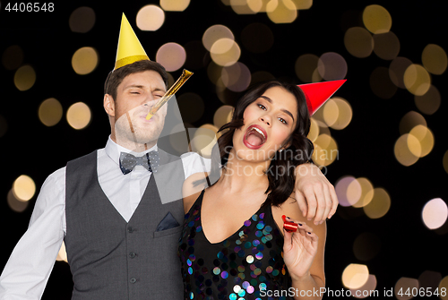 Image of happy couple with party blowers having fun