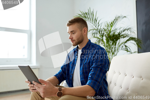 Image of man with tablet pc sitting on sofa at office