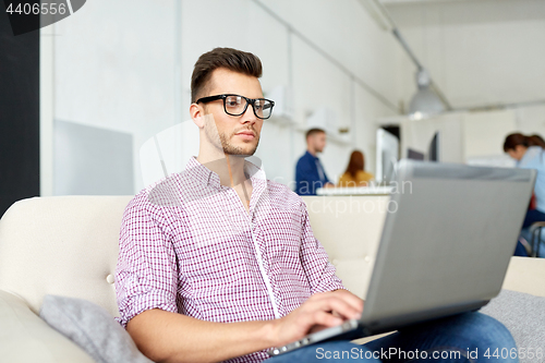Image of man in eyeglasses with laptop working at office