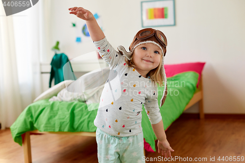 Image of happy little girl in pilot hat playing at home