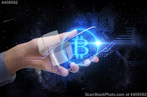 Image of close up of hand with smartphone and bitcoin