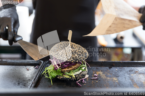 Image of Chef preparing burgers at grill plate on international urban street food festival.