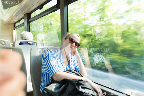 Image of Portrait of tired woman sleeping on bus.