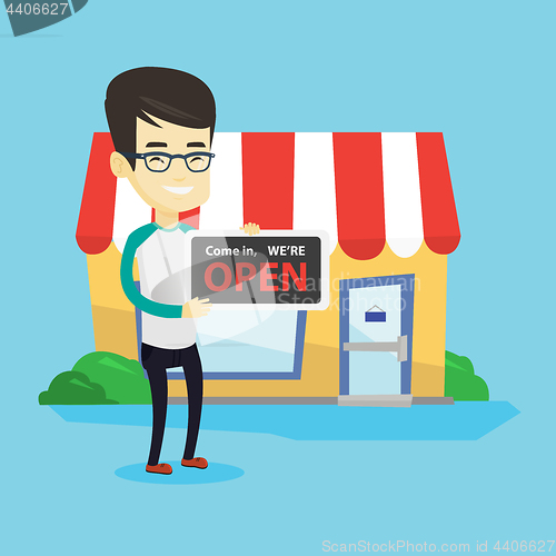 Image of Asian shop owner holding open signboard.