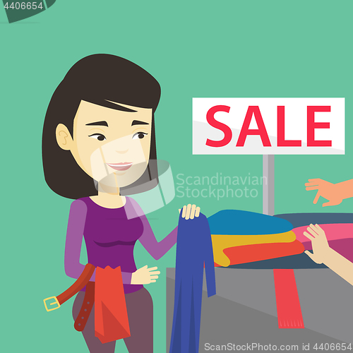 Image of Young woman choosing clothes in shop on sale.