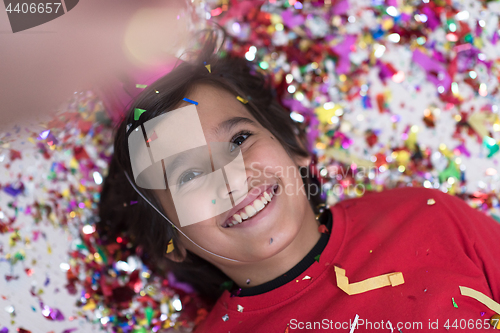 Image of kid blowing confetti while lying on the floor