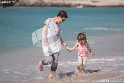 Image of mother and daughter running on the beach