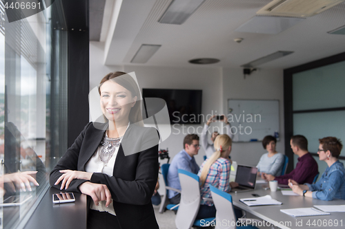 Image of Elegant Woman Using Mobile Phone by window in office building