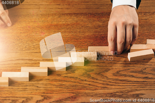 Image of Man and wooden cubes on table. Management concept