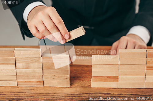 Image of Man and wooden cubes on table. Management concept