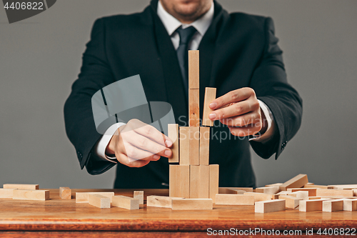 Image of Man and wooden cubes on table. Management concept