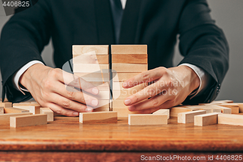 Image of Man and wooden cubes on table. Management concept