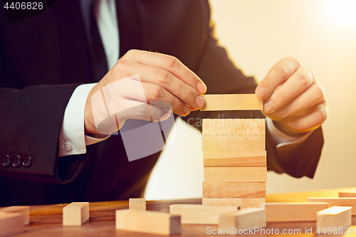 Image of Man and wooden cubes on table. Management concept