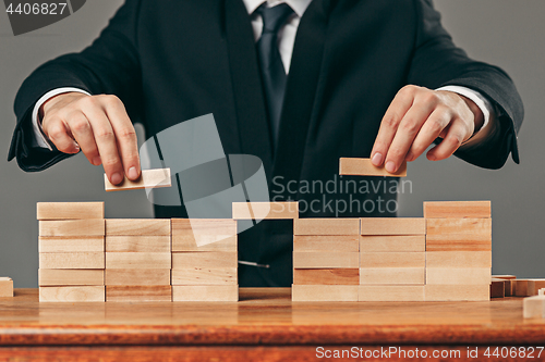 Image of Man and wooden cubes on table. Management concept