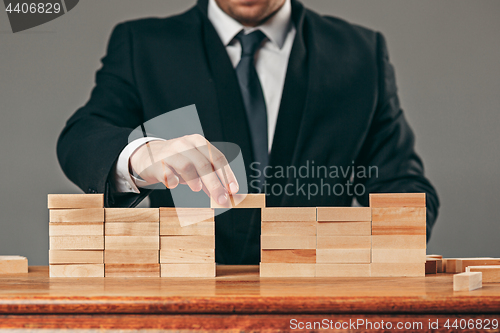 Image of Man and wooden cubes on table. Management concept