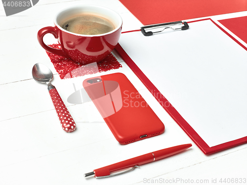 Image of Office table desk with set of colorful supplies, white blank note pad, cup, pen on white background.