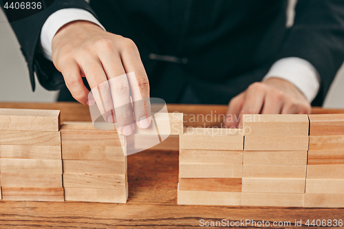 Image of Man and wooden cubes on table. Management concept