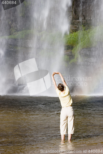 Image of Woman doing gymnastics in front of a waterfall