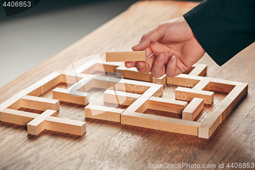 Image of Man and wooden cubes on table. Management concept