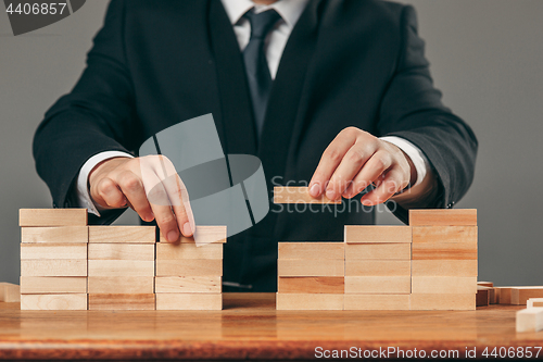 Image of Man and wooden cubes on table. Management concept