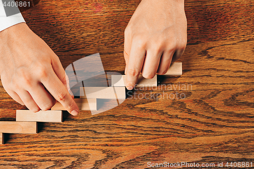 Image of Man and wooden cubes on table. Management concept