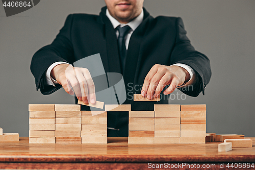 Image of Man and wooden cubes on table. Management concept