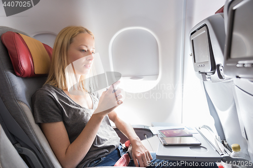 Image of Woman drinking coffee on commercial passengers airplane during flight.