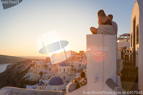 Image of Couple watching sunrise and taking vacation photos at Santorini island, Greece.
